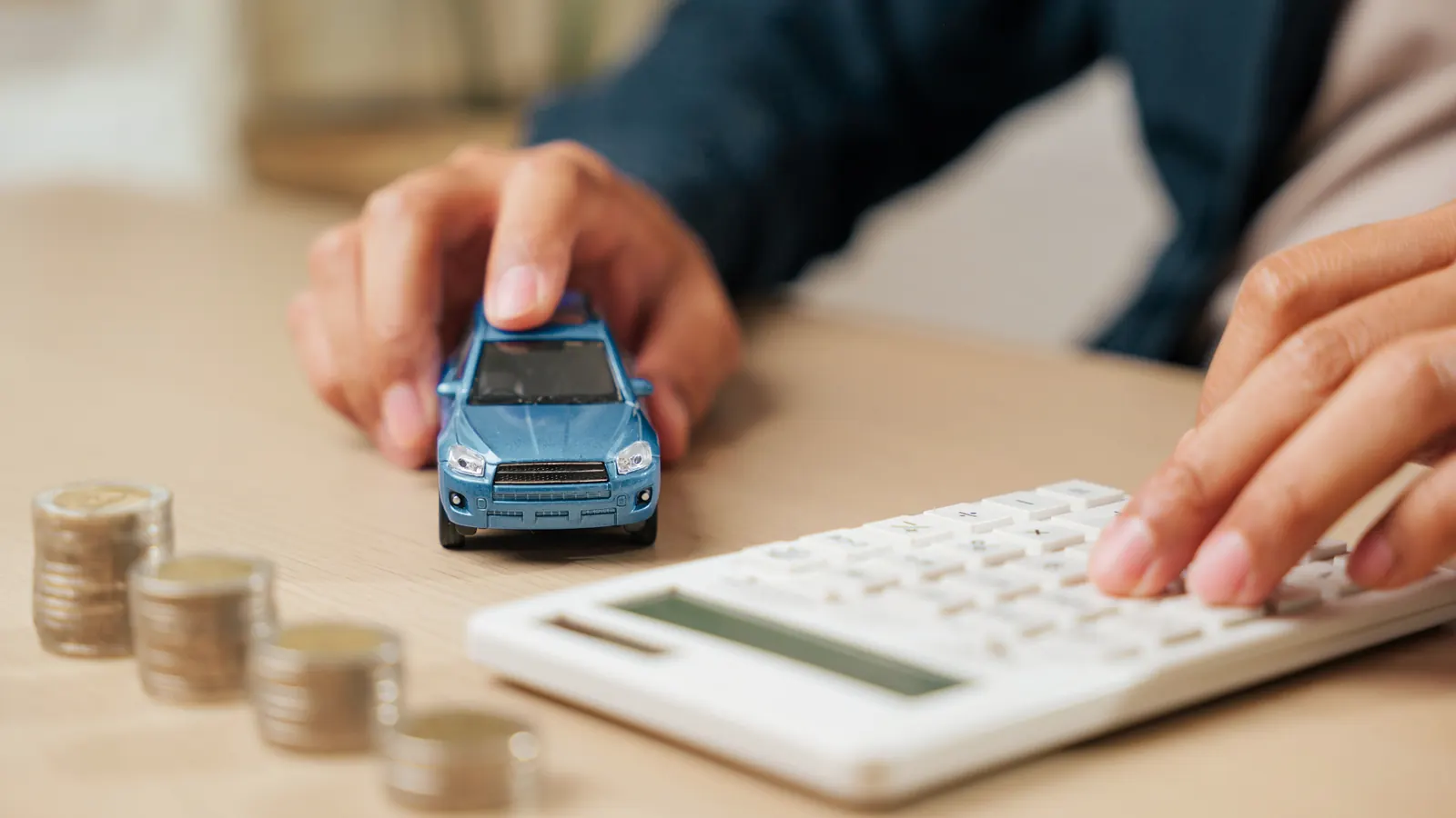 Carro em miniatura ao lado de calculadora e moedas